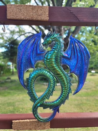 Shiny blue and green dragon with wings outstretched and twisting tail