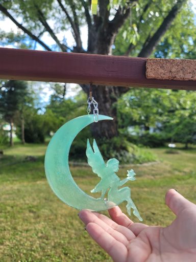 Green fairy sitting on a green cresent moon