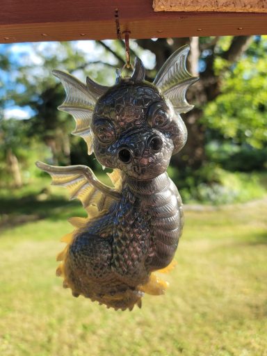 Black baby dragon with yellowish hue on claws, spine and wings