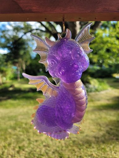 Purple baby dragon with hues of orange on the chest, claws, spine and wings