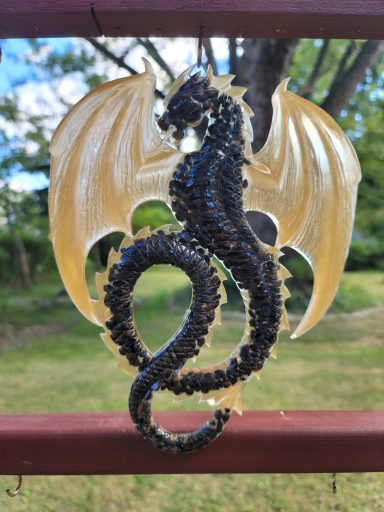 Black with hints of blue dragon with wings outstretched and twisting tail