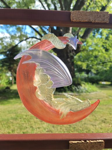 Yellow dragon with purple wings on a red cresent  moon snoozing